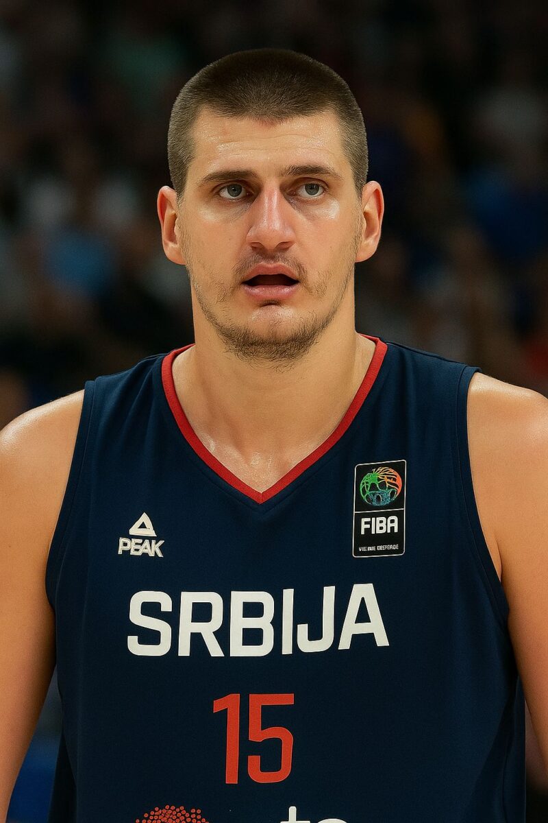Nikola Jokić u tamnoplavom dresu reprezentacije Srbije, sa brojem 15 i FIBA oznakom, fokusiran tokom utakmice na terenu.