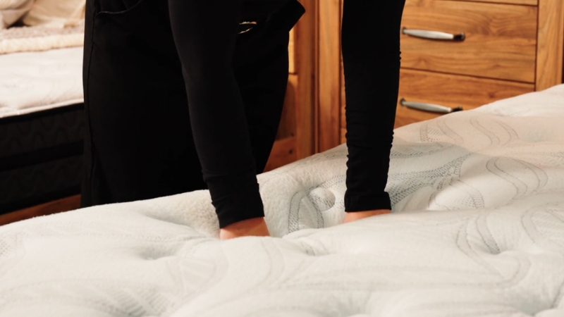 Žena rukama testira dušek u prodavnici pre kupovine