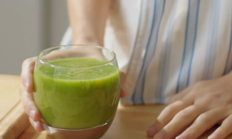 Osoba drži čašu detoksa u kuhinji