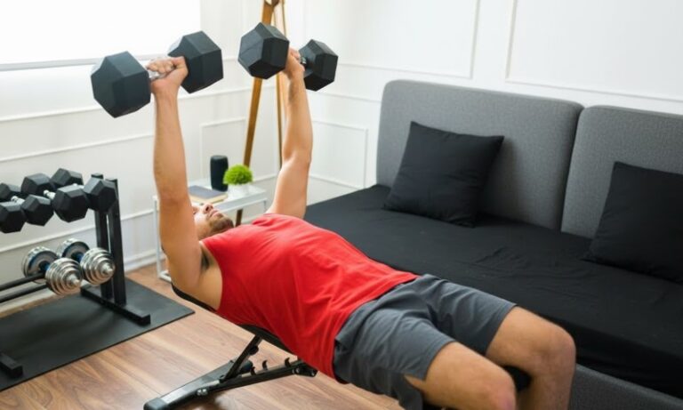 Muškarac u dvadesetim godinama radi vežbe benč presa u kućnoj teretani