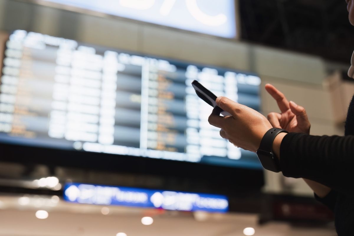 osoba proverava koliko će joj kasniti let na aerodromu